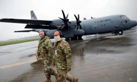 Hai quân nhân Mỹ đi cạnh chiếc trực thăng vận tải C-130 trong căn cứ quân sự Yokota, Nhật Bản. (Ảnh: Reuters)