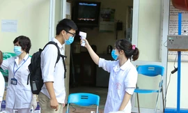 Tình nguyện viên đo thân nhiệt cho thí sinh tại kì thi tốt nghiệp THPT 2020