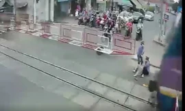 Cụ bà được 2 nữ gác chắn kéo ra khỏi đường sắt ngay trước mũi tàu. Ảnh cắt từ clip.