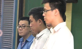 Ngô Thanh Long (áo xanh) và các bị cáo trong ngày đầu của phiên tòa. Ảnh: Tân Châu.