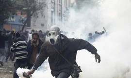Một người biểu tình ném trả lựu đạn cay về phía cảnh sát. Ảnh: AP