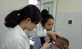 Bác sĩ Vũ Quế Anh đang xem xét tình trạng hoại tử của bé Kiên trước khi phẫu thuật cắt bỏ hoàn toàn. Ảnh: Đinh Tuấn.