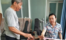 Nghệ sĩ Chí Tài và nghệ nhân làm đàn Ngọc Thức bên cây ghi ta (Ảnh tư liệu của gia đình nghệ nhân)