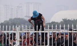 Một CĐV bám chặt hàng rào mong tới lượt mua được vé bóng đá. Ảnh: VSI