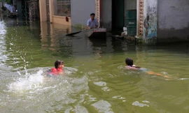 Hai đứa trẻ bơi giữa đường ngập lụt ở xóm Bến Vôi, thôn Cấn Hạ (xã Cấn Hữu, Quốc Oai, Hà Nội). Ảnh: Trường Phong