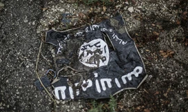 Cờ của IS bị đất đá vùi lấp trong khu vực xung đột. Ảnh: Sputnik