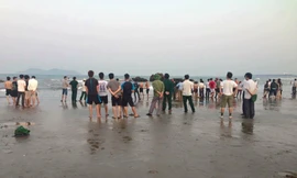 Người dân tập trung nơi bãi biển xảy ra vụ hai học sinh bị sóng cuốn mất tích khi đi chụp ảnh kỷ yếu.