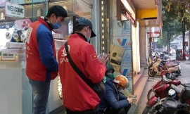 Các shipper của Grab và GoViet đang xếp hàng nhận đơn từ một cửa hàng đồ uống trên đường Quang Trung, Hà Đông, Hà Nội Ảnh: Võ Hóa 