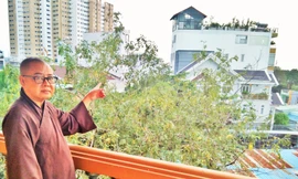 Hòa thượng Thích Từ Trí chỉ một ngôi nhà cao tầng đã xây dựng trên đất chùa cổ Giác Lâm Ảnh: Trần Nguyên Anh 