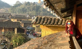 Du khách thích thú khi chụp ảnh với nhà trình tường tại Lô Lô Chải (xã Lũng Cú, huyện Đồng Văn). Ảnh: Nguyễn Việt Dũng