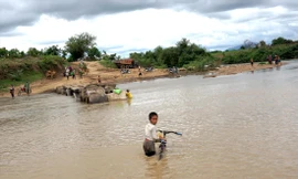 Em nhỏ dắt xe đạp vượt sông