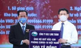 Anh hùng Lao động Lê Văn Kiểm, Chủ tịch Hội đồng quản trị Công ty CP Đầu tư và Kinh doanh Golf Long Thành (trái) trao tặng quỹ vắc-xin phòng, chống COVID-19 số tiền 500 tỷ đồng