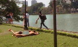 Hai nữ du khách mặc bikini tắm nắng bên Hồ Gươm