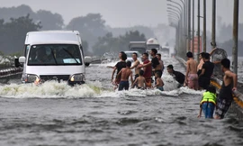 Đùa giỡn trước đầu ôtô trên con đường ngập nước ở Hà Nội