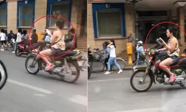 Cô gái vừa chạy xe máy vừa đọc sách trên đường phố Hà Nội