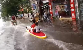 Hai em bé ngồi thuyền lướt sóng trên phố đông 