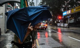 Một cụ bà che ô đứng đợi taxi tại Hồng Kông sáng 16/9. Ảnh: Getty