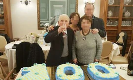 "Bố già" Di Maggio cầm ly uống rượu, chụp ảnh bên chiếc bánh kem hình số 100.