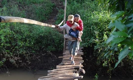 Chồng thót tim cõng vợ bại liệt băng qua cầu ọp ẹp mỗi ngày