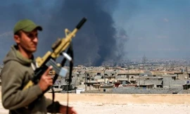 Một binh sỹ Iraq đứng trên nóc một tòa nhà ở tây Mosul, phía sau khói đạn bốc lên mù mịt. Ảnh: AFP