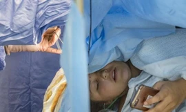 Jess Banik đang sử dụng điện thoại trong khi các bác sĩ đang tiến hành ca phẫu thuật não cho cô