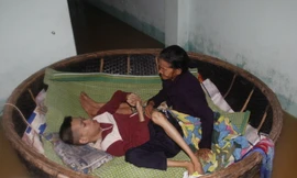 Hai mẹ con bà Đắt trong chiếc thuyền thúng nổi trôi theo nước lũ. Ảnh: Thanh Trần. 