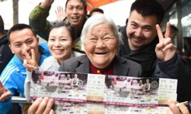 Cụ bà vui mừng khi mua được hai tấm vé xem bóng đá cho con.