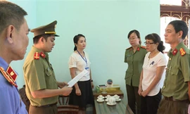 Bị can Nguyễn Thị Hồng Nga (áo trắng bên phải) nghe tống đạt quyết định khởi tố