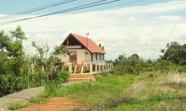 Nhà cộng đồng trơ trọi giữa bãi đất trống cỏ mọc um tùm 