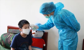 Quân y Bùi Thị Thắm kiểm tra thân nhiệt cho một cháu nhỏ trong khu cách ly ẢNH: PV 