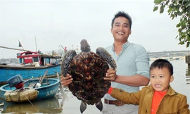 Cha con anh Nguyễn Văn Đoàn giao lại con rùa quý hiếm cho cơ quan chức năng để thả về lại biển. Ảnh: QH