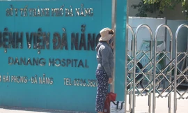 Một người nhà bệnh nhân đứng trước cổng bệnh viện sau khi bệnh viện này được cách ly y tế. Ảnh: Nguyễn Thành