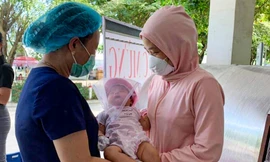 Mẹ cháu bé đón con từ tay nhân viên y tế bệnh viện Hoà Vang. 