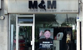 Tấm poster khuyến mại in hình lãnh đạo Triều Tiên Kim Jong Un treo trước cửa hàng tạo mẫu tóc M&M