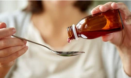 Một người phụ nữ đi ngang qua cánh cổng đóng kín của Goel Pharma Chem, công ty kinh doanh hóa chất đã cung cấp nguyên liệu cho hãng Maiden Pharmaceuticals sản xuất các loại xi-rô ho liên quan đến cái chết của nhiều trẻ em. (Ảnh: Reuters)