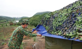 Trung tá quân nhân chuyên nghiệp Bùi Văn Bách tháo nước đọng trên mái che lán dã chiến Ảnh: Nguyễn Minh