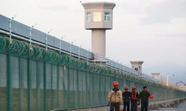 Một nhóm công nhân đi dọc hàng rào của trung tâm cải tạo ở Tân Cương Ảnh: Reuters