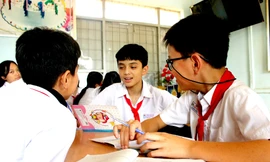 Em Quốc (giữa) trao đổi bài học với các bạn cùng lớp 