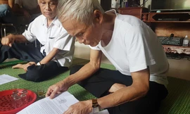 Ông Nguyễn Thái Tưởng lật giở từng trang giấy kể lại chuyện 40 năm của xóm 