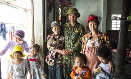 Gia đình bà Dương Thị Doát, trong đó có một thai phụ được biên phòng Ngư Thủy cứu sống khi cả nhà đang ngồi trên chiếc giường treo. Ảnh: Văn Chương