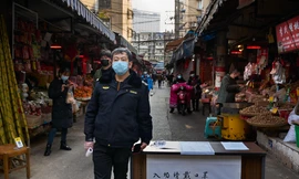 Nhân viên an ninh trực đo thân nhiệt tại cổng một chợ hải sản ở Vũ Hán ảnh: thesun.co.uk 