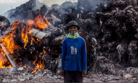 Một người làm nghề nhặt rác ở Indonesia đứng trước núi rác thải nhập khẩu đang bị đốt ảnh: EPA
