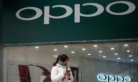 Một phụ nữ đứng trước một cửa hàng của hãng điện thoại Oppo. Ảnh: Reuters 