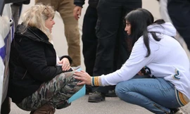 Một phụ nữ nức nở bên xe cảnh sát tại hiện trường vụ tấn công. Ảnh: CNN