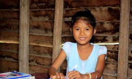 Em Siu H’Han ngồi học bài trong căn nhà sàn cũ nát