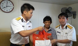 Thuyền trưởng Lê Văn Chung (bên trái) động viên, trao quà cho ngư dân tàu cá bị nạn, năm 2018