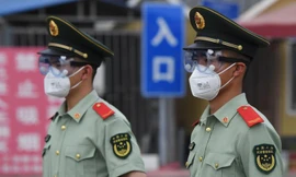 Cảnh sát bán quân sự đeo khẩu trang, kính bảo hộ khi đứng gác tại cổng chợ đầu mối Tân Phát Địa ở Bắc Kinh hôm 13/6. Ảnh: Getty Images 