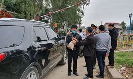 Linh mục Hoàng Trọng Hữu (bìa trái) cầm túi bánh khi vào khu vực tâm dịch. Ảnh: F.X 