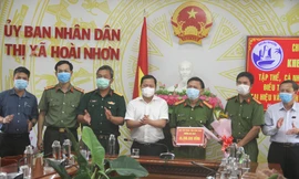 Chủ tịch UBND tỉnh Bình Định Nguyễn Phi Long khen thưởng cho tập thể, cá nhân có thành tích xuất sắc điều tra, phá vụ án trộm cắp tài sản tại hiệu vàng Anh Trung. Ảnh: Trương Định