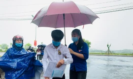 Cảm động tình nguyện viên che ô cho thí sinh giữa trời mưa lớn